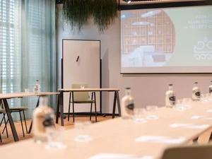 Zeller’s Quartier: das besondere Tagungshotel in Bayern Konferenzraum mit Tischen, Stühlen, Wasserflaschen und Projektionsleinwand
