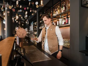 Barkeeper an der Cervus Bar Mitarbeiter an der Bar im Restaurant Cervus bereitet hinter der Holztheke Getränke vor.