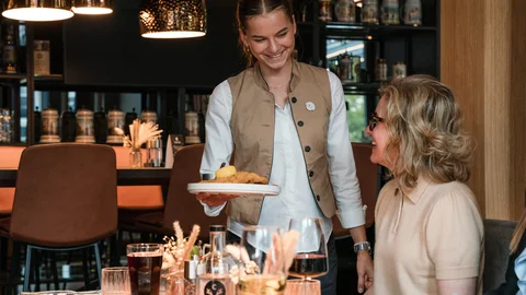 Kellnerin serviert einem Gast in einem Restaurant ein Gericht mit Lächeln