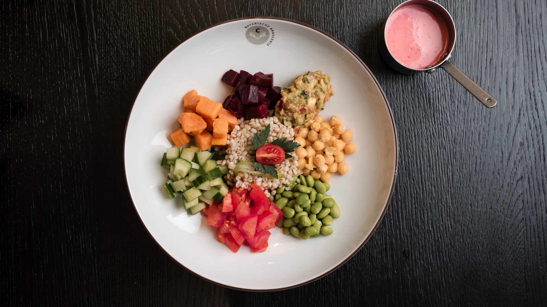 colorful vegetable salad with grains and red sauce in small pan on dark table