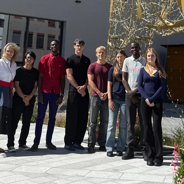 Die sieben neuen Auszubildenden stehen vor dem Hotel & Restaurant unter unserem Leuchthirsch "Hirschbert".