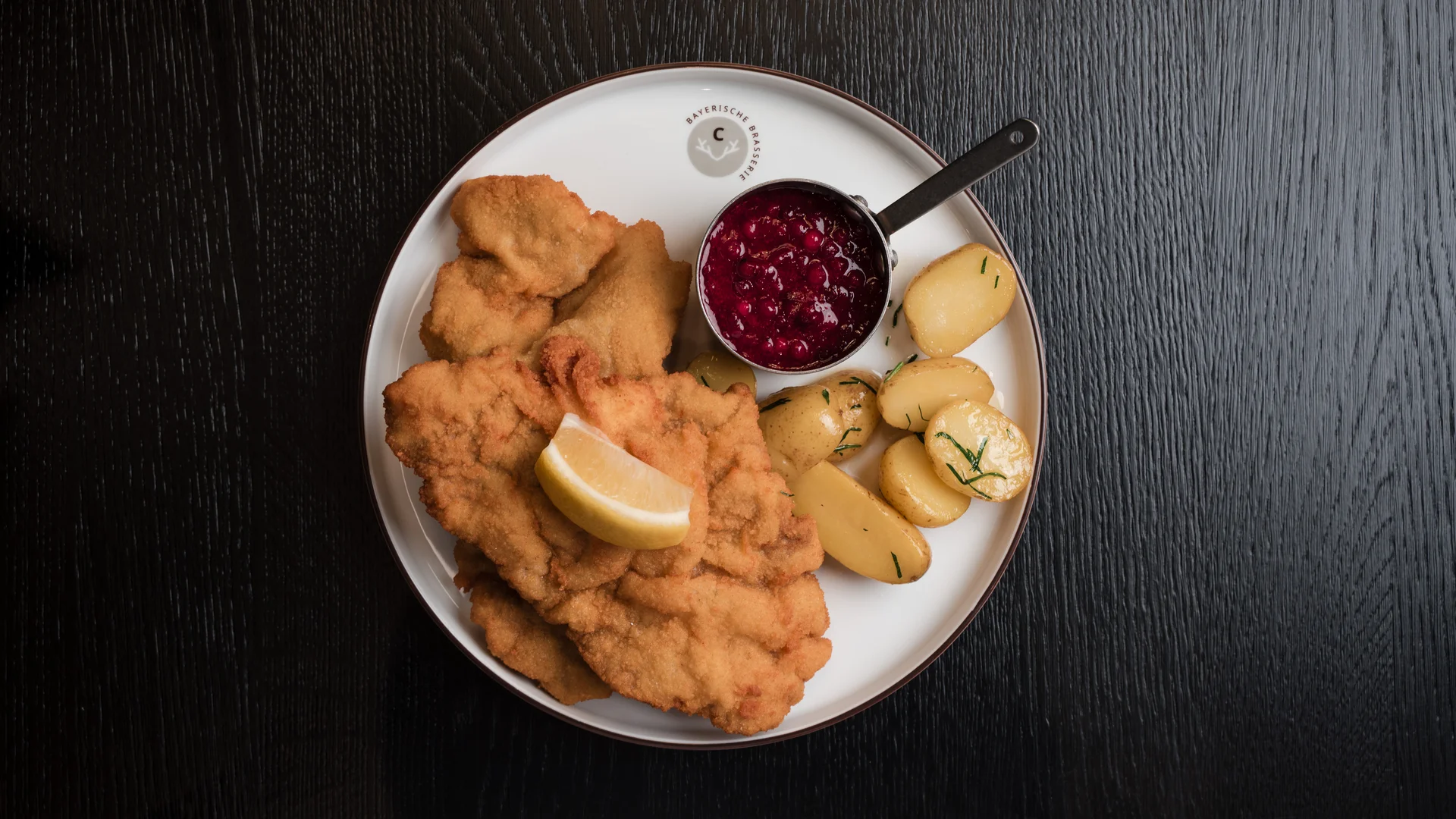 Speisekarte Teller mit Wiener Schnitzel, Bratkartoffeln, Preiselbeersauce und Zitronenscheibe