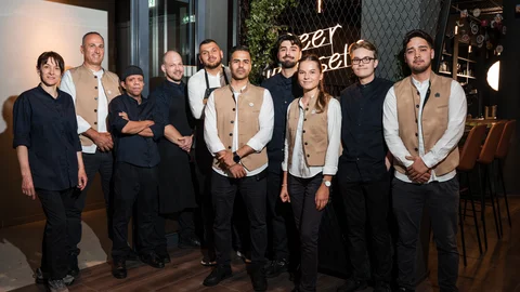 Gruppenfoto von Restaurantmitarbeitern in Uniform vor Wand mit Neonlicht