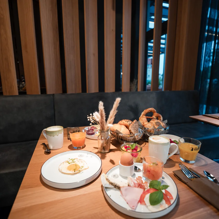 Ihr Start in den Tag: Frühstück in Königsbrunn Frühstückstisch mit Eiern, Aufschnitt, Brötchen, Kaffee und Säften im Café