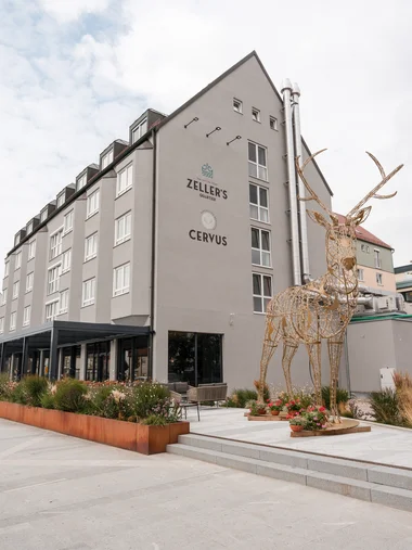 Moderne Gebäude mit Metallskulptur eines Hirsches und bepflanztem Vorgarten