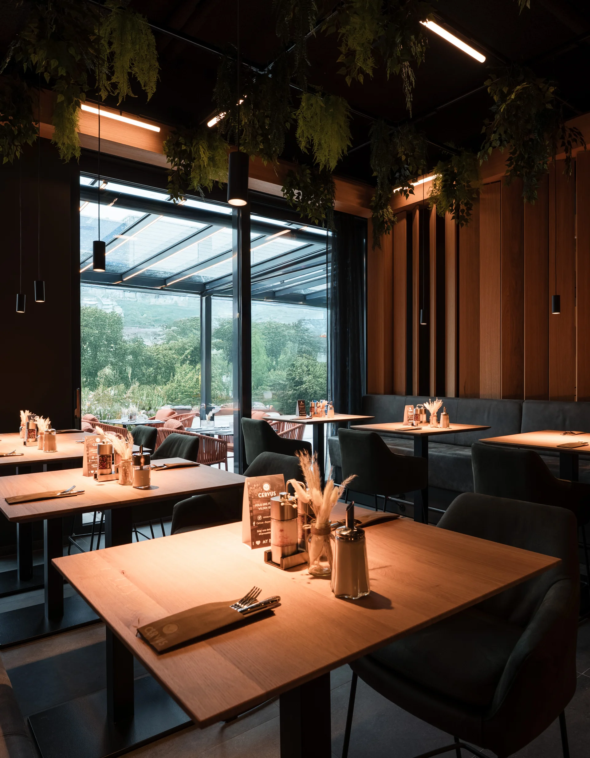 Modernes Restaurant mit Holzmöbeln und Pflanzen an der Decke